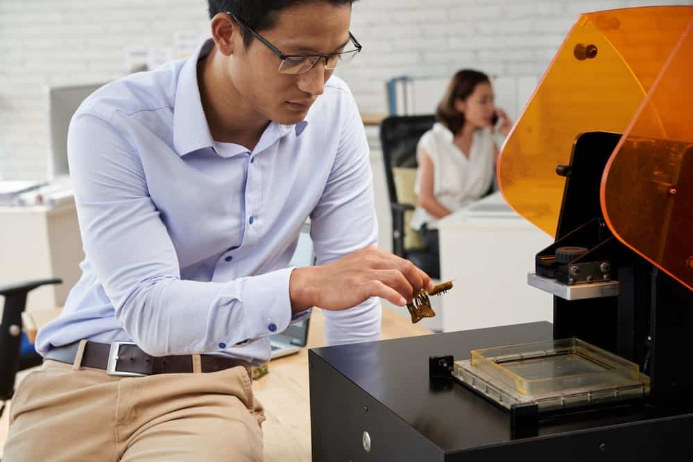 Asiático joven tomando forma de plástico de la impresora 3D - impresoras 3d profesionales
