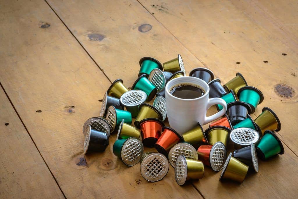Taza de cafe rodeada de capsulas de cafe